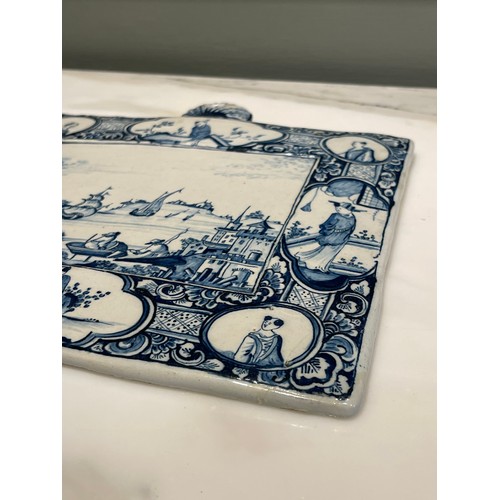 97 - A Dutch Delft blue and white rectangular genre plaque. Central marine landscape of port and figures ... 