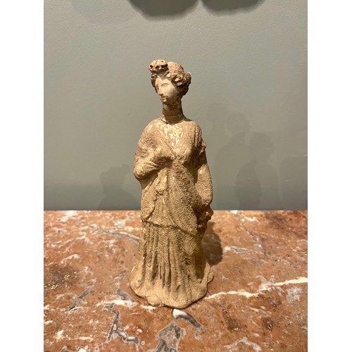 101 - A Hellenistic terracotta statuette of a woman wearing a chiton. Evidence of polychromy. Condyli... 