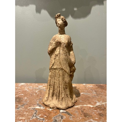 101 - A Hellenistic terracotta statuette of a woman wearing a chiton. Evidence of polychromy. Condyli... 