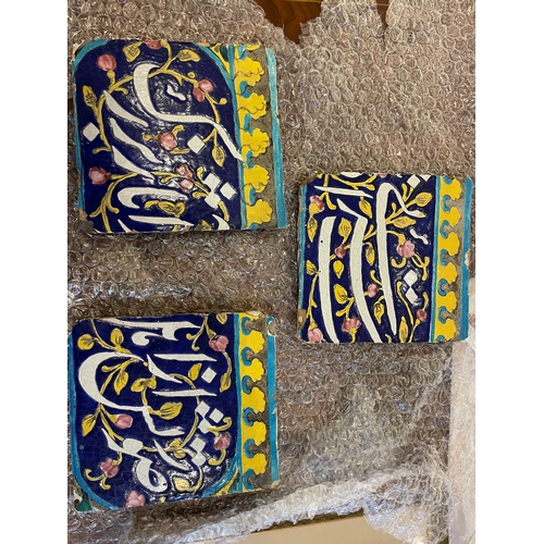 143 - Qajar19th CenturyThree calligraphic pottery tilesBlue ground with white calligraphy and yellow and t... 