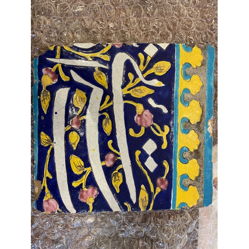 143 - Qajar19th CenturyThree calligraphic pottery tilesBlue ground with white calligraphy and yellow and t... 