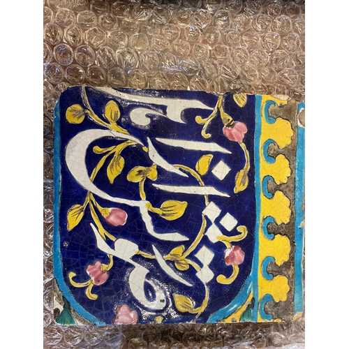 143 - Qajar19th CenturyThree calligraphic pottery tilesBlue ground with white calligraphy and yellow and t... 