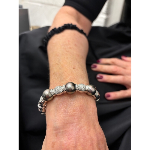 63 - A Tahitian grey pearl and brilliant cut diamond bangleSet to the front with three large cultured pea... 