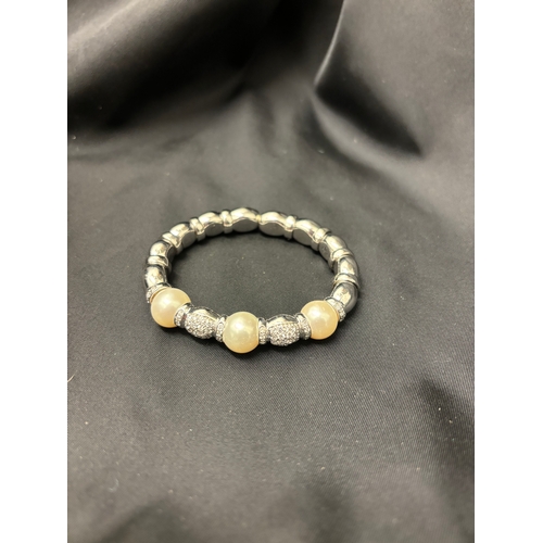 64 - A Tahitian pearl and brilliant cut diamond bangleSet to the front with three large cultured pearls w... 