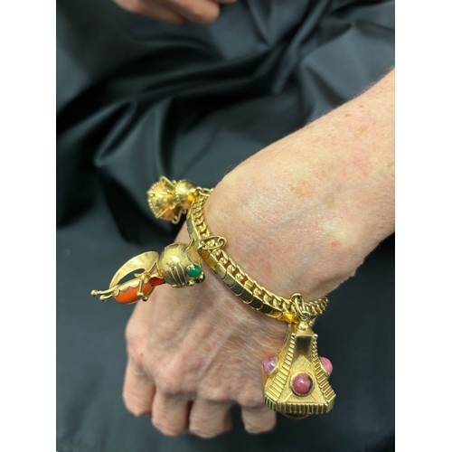 75 - An attractive 1950s gold charm bracelet with five large gem set charms To a flexible scaled curb lin... 