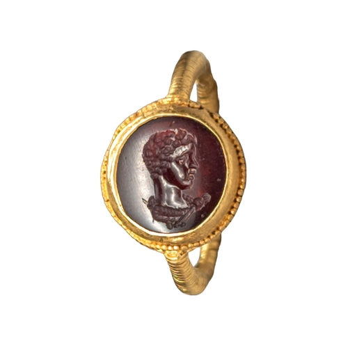 58 - A Roman carnelian intaglio engraved with a bust of Apollo or Caracalla in the guise of Apollo, set i... 