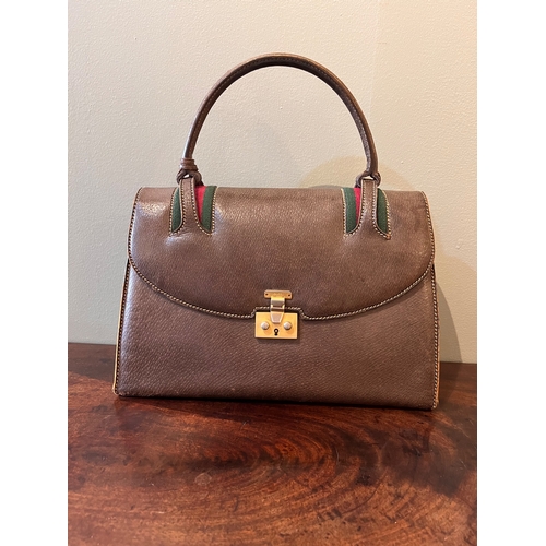 11 - GucciCirca 1960sA brown leather handbagWith single top handle, brass hardware, key and key purse, an... 