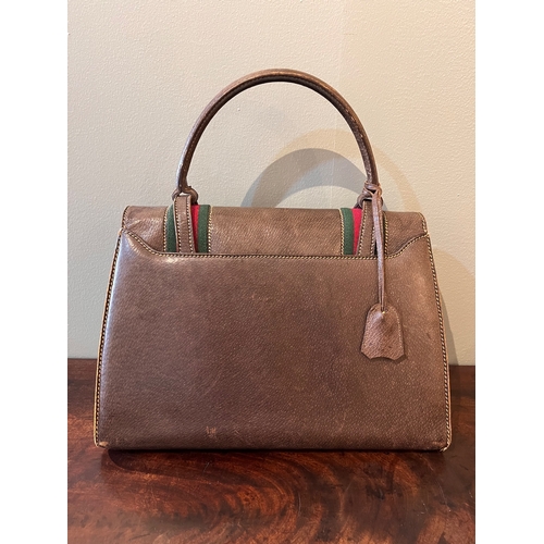 11 - GucciCirca 1960sA brown leather handbagWith single top handle, brass hardware, key and key purse, an... 