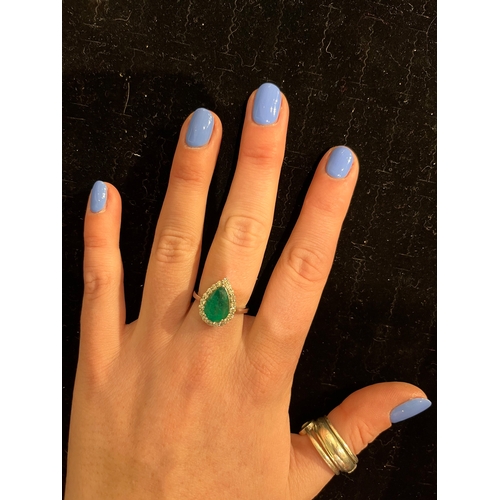 33 - A pear shaped emerald and diamond cluster ringThe pear shaped emerald of good colour within a surrou... 