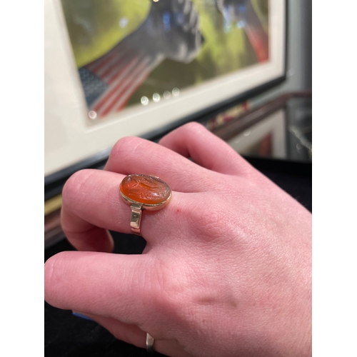 61 - A Roman pale carnelian intaglio of a male figure, possibly a solider? gazing down at a lidded vessel... 