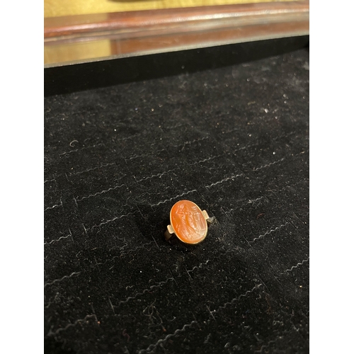 61 - A Roman pale carnelian intaglio of a male figure, possibly a solider? gazing down at a lidded vessel... 