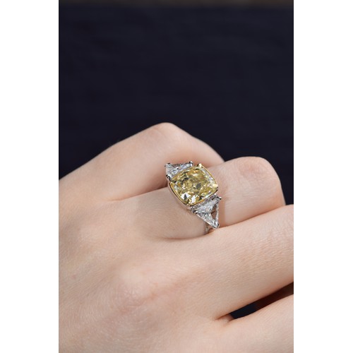 144 - EuropeanCirca 2000An impressive cushion-shaped yellow diamond and white diamond three-stone ringThe ... 