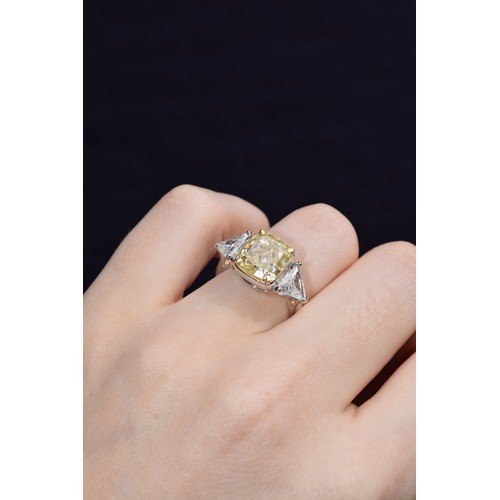 144 - EuropeanCirca 2000An impressive cushion-shaped yellow diamond and white diamond three-stone ringThe ... 