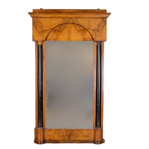 390 - BiedermeierA walnut pier mirrorWith an arch moulded crest and two ebony split turned columns To... 