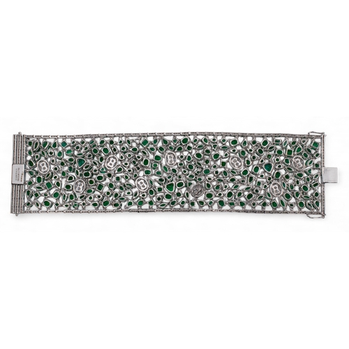 96 - Continental, Circa 1990A highly flexible material-like emerald and diamond bracelet.The wide bracele... 