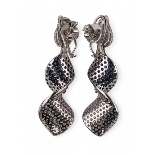 126 - Continental, ContemporaryA pair of sapphire and diamond pendant earrings designed as a ribbon twist.... 