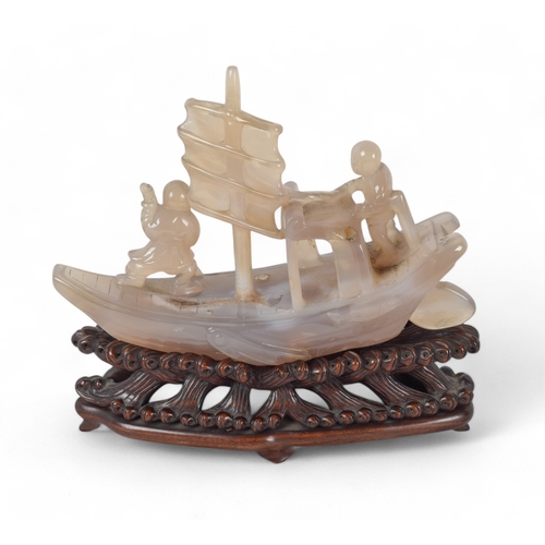 363 - Chinese, c. 1920A chalcedony model of a boat on an intricately carved honglu standTogether with a Ch... 