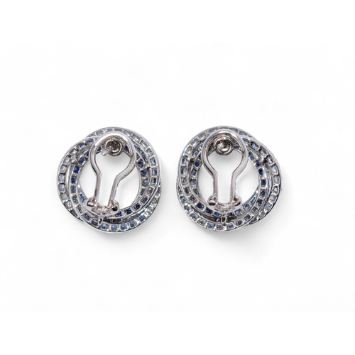 14 - Circa 1990sA pair of diamond two colour sapphire and 18 carat white gold entwined circle ear clips.T... 