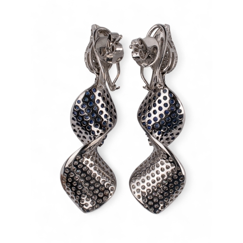 30 - Continental, ContemporaryA pair of sapphire and diamond pendant earrings designed as a ribbon twist.... 