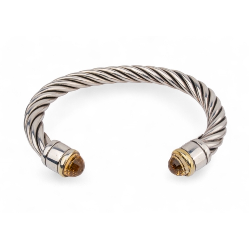 34 - ContemporaryA group of three silver twist gold and gem set bangles. The terminals set with topaz, ci... 