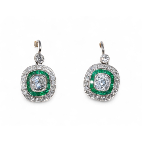 68 - EdwardianA pair of diamond and emerald cluster ear pendants, each centrally set with a cushion shape... 