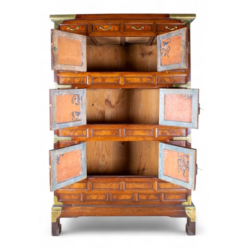 263 - Korean, AntiqueA tall three-tier cabinet with inset wood panels and brass butterfly handles and deco... 