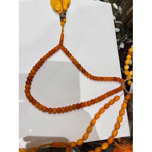 104 - A group of fourteen butterscotch amber and amber prayer bead necklaces. Some with gold and gilt meta... 