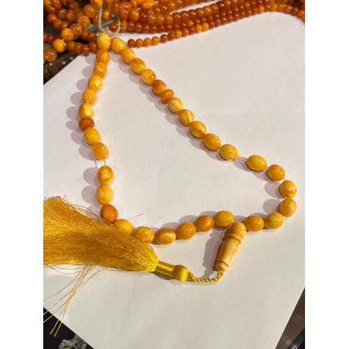 104 - A group of fourteen butterscotch amber and amber prayer bead necklaces. Some with gold and gilt meta... 