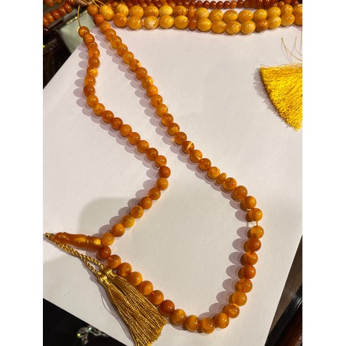 104 - A group of fourteen butterscotch amber and amber prayer bead necklaces. Some with gold and gilt meta... 