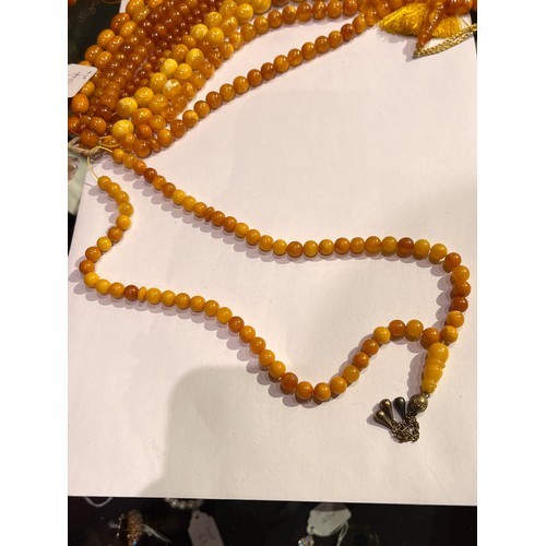 104 - A group of fourteen butterscotch amber and amber prayer bead necklaces. Some with gold and gilt meta... 