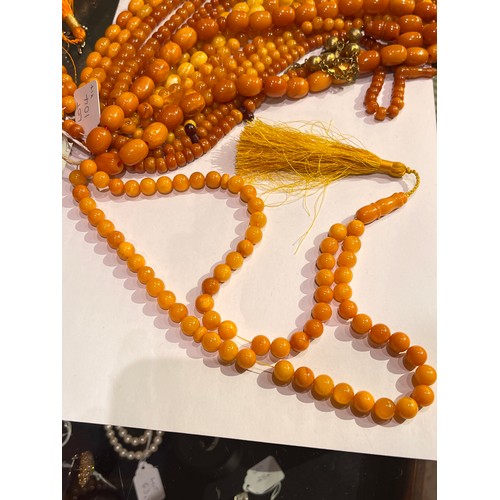 104 - A group of fourteen butterscotch amber and amber prayer bead necklaces. Some with gold and gilt meta... 