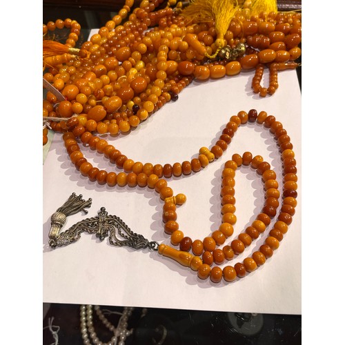 104 - A group of fourteen butterscotch amber and amber prayer bead necklaces. Some with gold and gilt meta... 