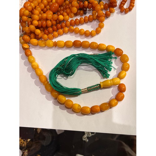 104 - A group of fourteen butterscotch amber and amber prayer bead necklaces. Some with gold and gilt meta... 