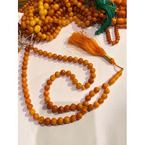 104 - A group of fourteen butterscotch amber and amber prayer bead necklaces. Some with gold and gilt meta... 