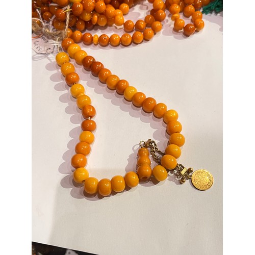 104 - A group of fourteen butterscotch amber and amber prayer bead necklaces. Some with gold and gilt meta... 