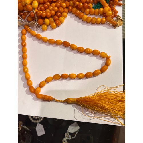 104 - A group of fourteen butterscotch amber and amber prayer bead necklaces. Some with gold and gilt meta... 