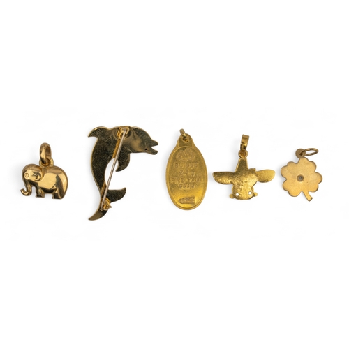 29 - A yellow gold dolphin brooch and four other gold charms, including a four-leaf clover charm set with... 