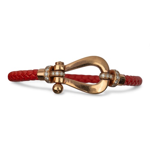 40 - ContemporaryAn 18 carat gold, diamond and leather bangleThe orange plaited leather with a stirrup sh... 