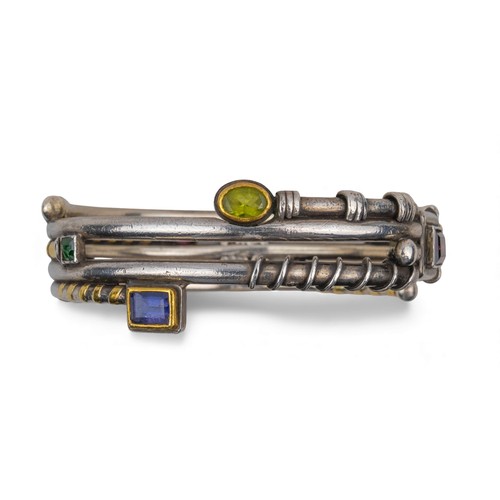 42 - Barbara BertagnolliA most unusual silver, gold and gem-set bangle. Set with multicoloured gemstones ... 