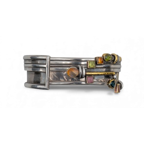 44 - Barbara BertagnolliA silver and gold multi gem-set stylised braceletDiameter: 69 mm.Total weight: Ap... 