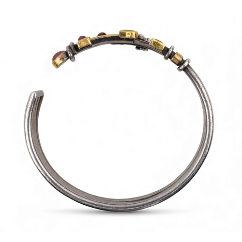 44 - Barbara BertagnolliA silver and gold multi gem-set stylised braceletDiameter: 69 mm.Total weight: Ap... 
