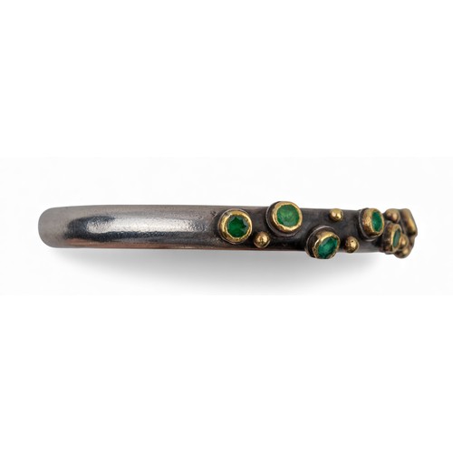 47 - Barbara BertagnolliAn emerald-set silver and gold bangle. The heavy silver torque applied with numer... 