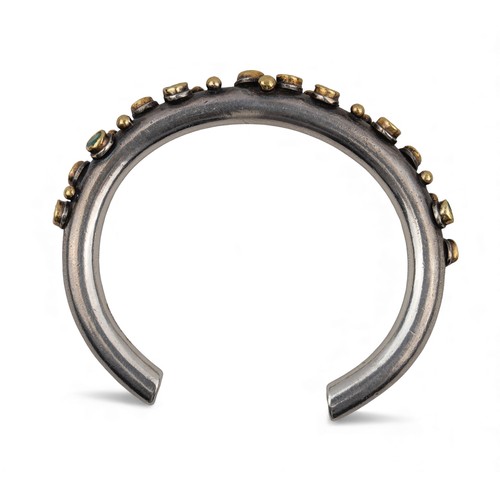 47 - Barbara BertagnolliAn emerald-set silver and gold bangle. The heavy silver torque applied with numer... 
