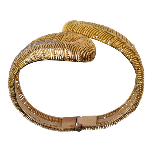 84 - A gold and diamond double feather bangle, circa 1960The wirework crossover feathers with a diamond-s... 
