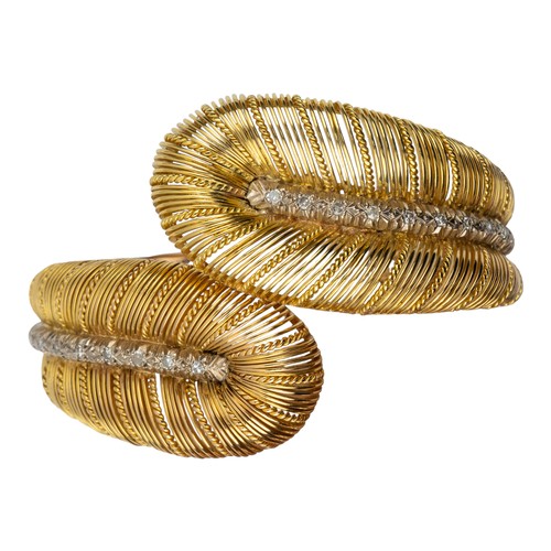 84 - A gold and diamond double feather bangle, circa 1960The wirework crossover feathers with a diamond-s... 