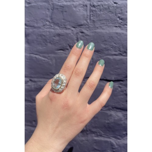 44 - An aquamarine and diamond cluster ring, circa 1960The oval-shaped mixed-cut aquamarine, weighing app... 