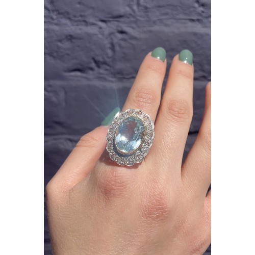 44 - An aquamarine and diamond cluster ring, circa 1960The oval-shaped mixed-cut aquamarine, weighing app... 