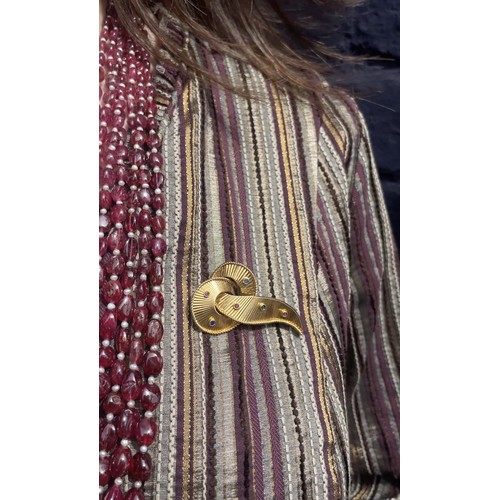 33 - A gold and gem-set brooch, circa 1940sDesigned as a bright-cut fluted gold scroll, with wirework bor... 
