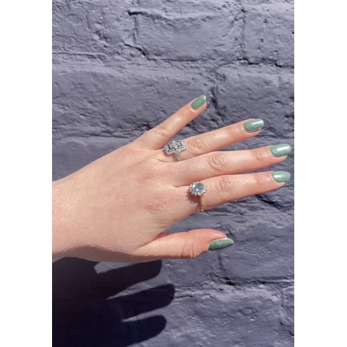 41 - An aquamarine and diamond cluster ring, circa 1980sThe oval-shaped mixed-cut aquamarine of pretty co... 