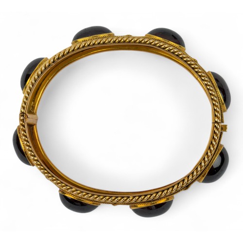 7 - Antique, An impressive cabochon garnet and gold bangle, circa 1870The Etruscan-style bloomed gold wi... 